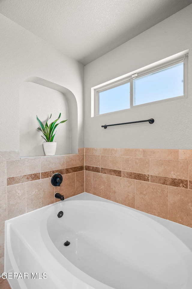 bathroom with a bathing tub and a textured ceiling