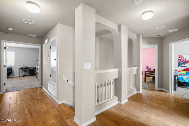 hallway featuring a textured ceiling and light hardwood / wood-style flooring