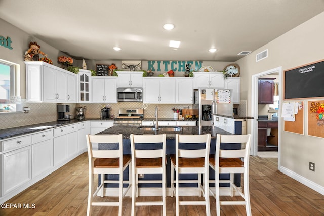 kitchen with sink, light hardwood / wood-style flooring, an island with sink, appliances with stainless steel finishes, and a breakfast bar area