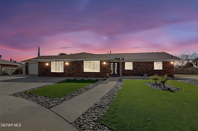 ranch-style home with a garage and a lawn