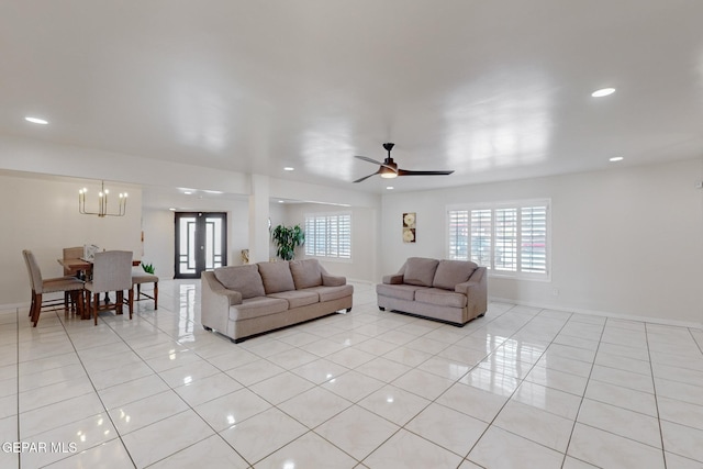 tiled living room with ceiling fan with notable chandelier