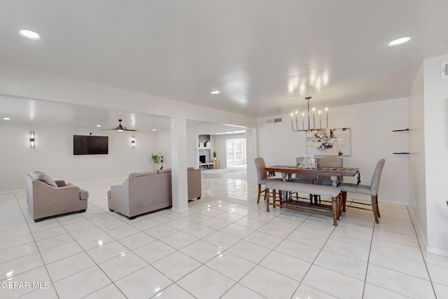 dining room with a fireplace, ceiling fan with notable chandelier, and light tile patterned flooring