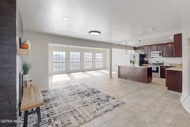 kitchen featuring stainless steel appliances, sink, light tile patterned floors, decorative light fixtures, and a center island