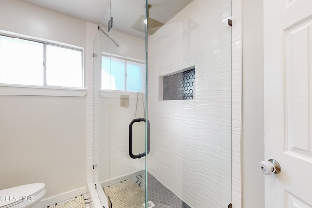 bathroom with tile patterned flooring, toilet, and a shower with shower door