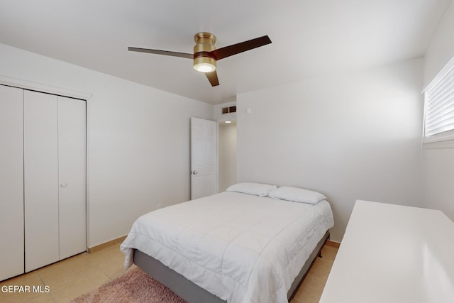 tiled bedroom with ceiling fan and a closet