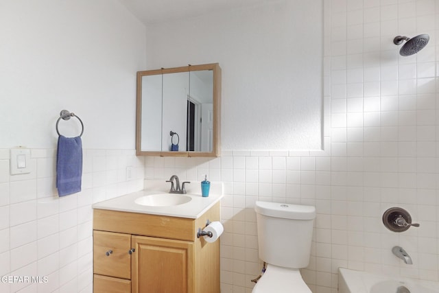 full bathroom with vanity, toilet, tile walls, and tiled shower / bath combo