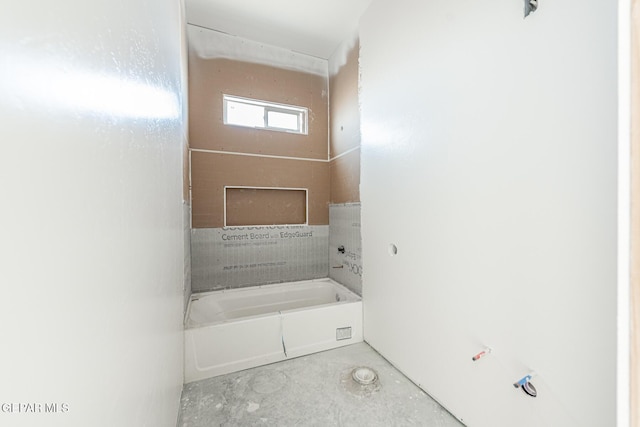 bathroom with a bath and concrete floors