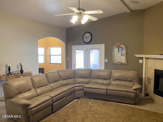 tiled living room featuring beamed ceiling, ceiling fan, and a fireplace