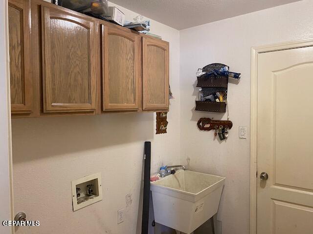 laundry room with hookup for a washing machine, sink, and cabinets