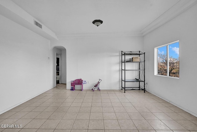 tiled spare room featuring ornamental molding