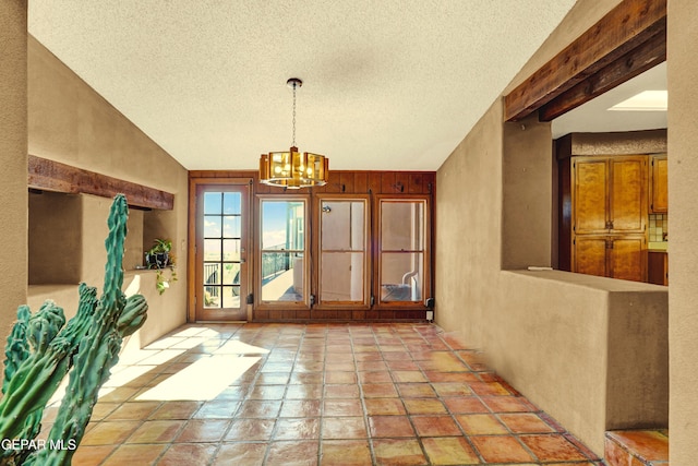 dining room with a notable chandelier, a textured ceiling, and wooden walls