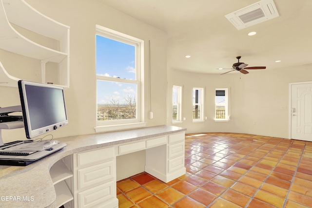 unfurnished office featuring ceiling fan, light tile patterned flooring, and built in desk