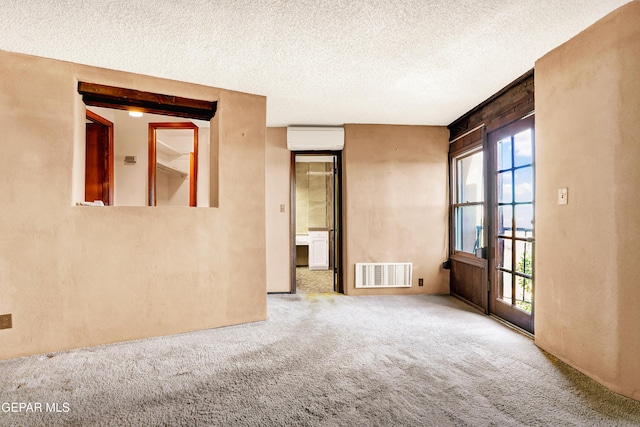 carpeted empty room with a wall mounted air conditioner and a textured ceiling