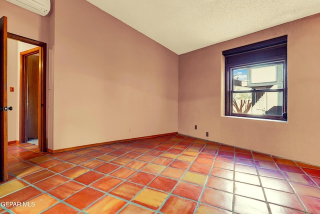 spare room featuring a wall mounted air conditioner, a textured ceiling, and vaulted ceiling