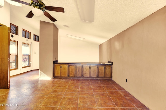 empty room featuring ceiling fan, a textured ceiling, and vaulted ceiling