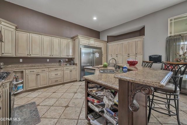 kitchen with light stone countertops, sink, stainless steel appliances, a breakfast bar, and a center island with sink