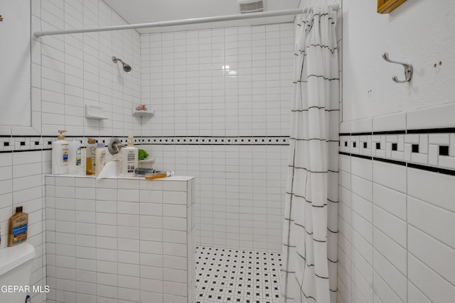 bathroom with a shower with shower curtain and tile walls