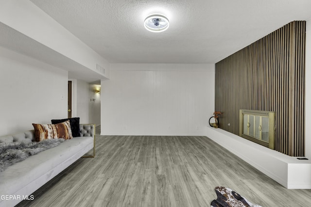 living room with wooden walls, light hardwood / wood-style flooring, and a textured ceiling