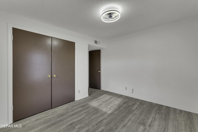 unfurnished bedroom with a closet, a textured ceiling, and light hardwood / wood-style flooring