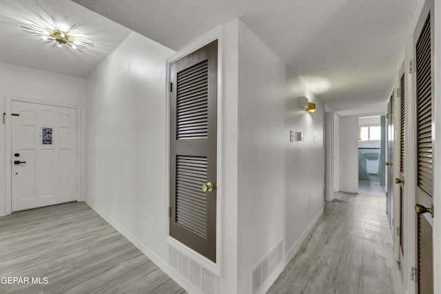 hallway featuring a textured ceiling and light hardwood / wood-style floors