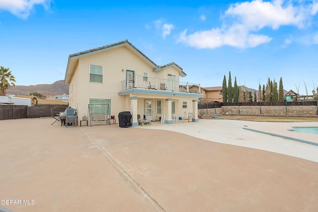 back of house featuring a mountain view, a balcony, and a patio area