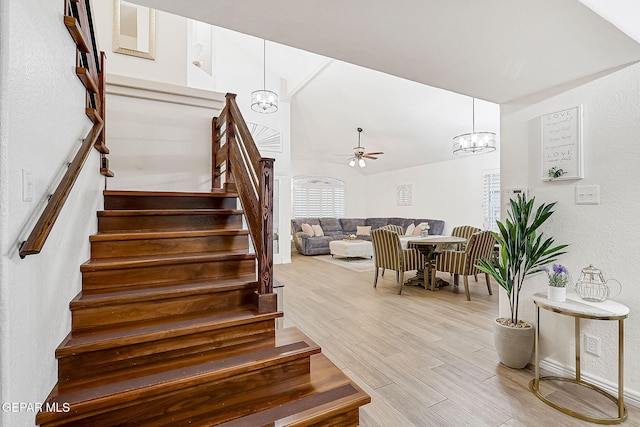 staircase with ceiling fan with notable chandelier and hardwood / wood-style flooring