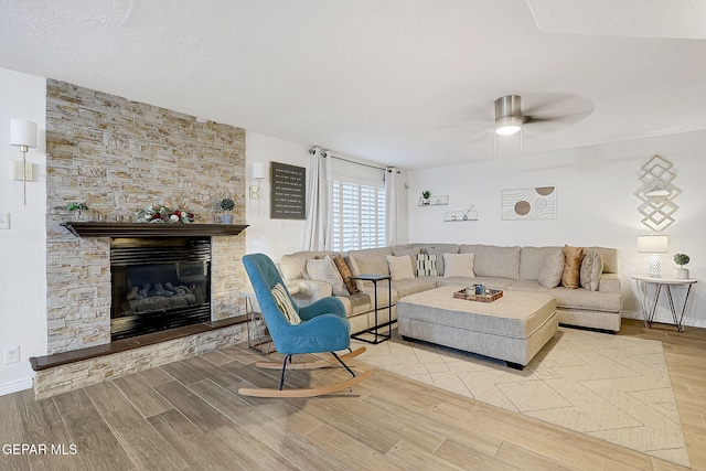 living room with ceiling fan, a fireplace, and a textured ceiling