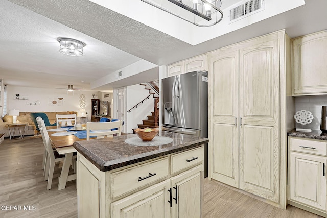 kitchen featuring cream cabinetry, ceiling fan, a kitchen island, and stainless steel fridge with ice dispenser