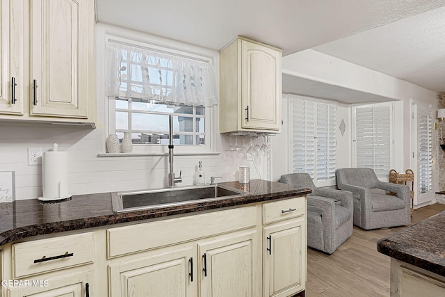 kitchen featuring backsplash, cream cabinets, sink, and light hardwood / wood-style floors