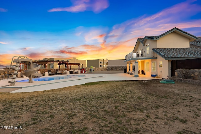 pool at dusk featuring a pergola, a patio area, a yard, and a water slide