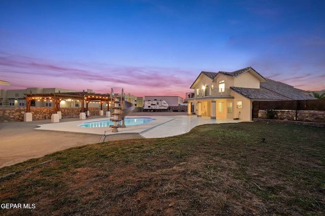 pool at dusk featuring a lawn, a patio, and a water slide