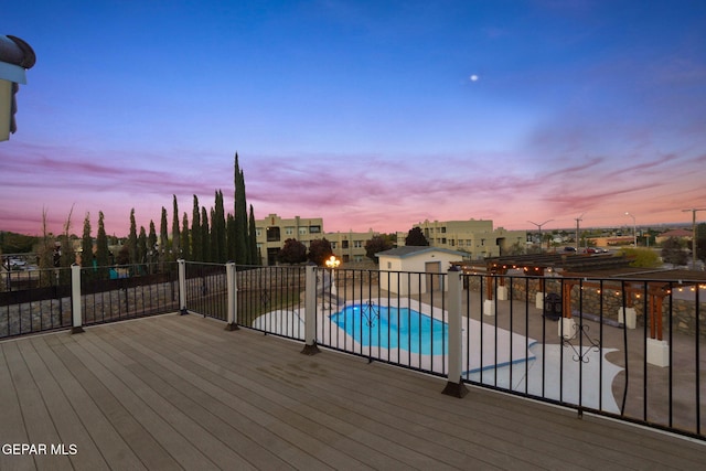 deck at dusk with a fenced in pool