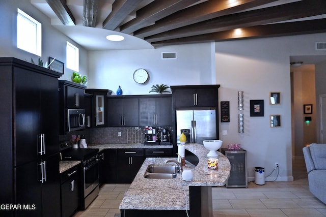 kitchen featuring decorative backsplash, sink, an island with sink, and stainless steel appliances