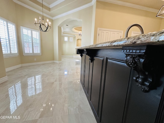 kitchen featuring a chandelier, pendant lighting, light stone countertops, and crown molding