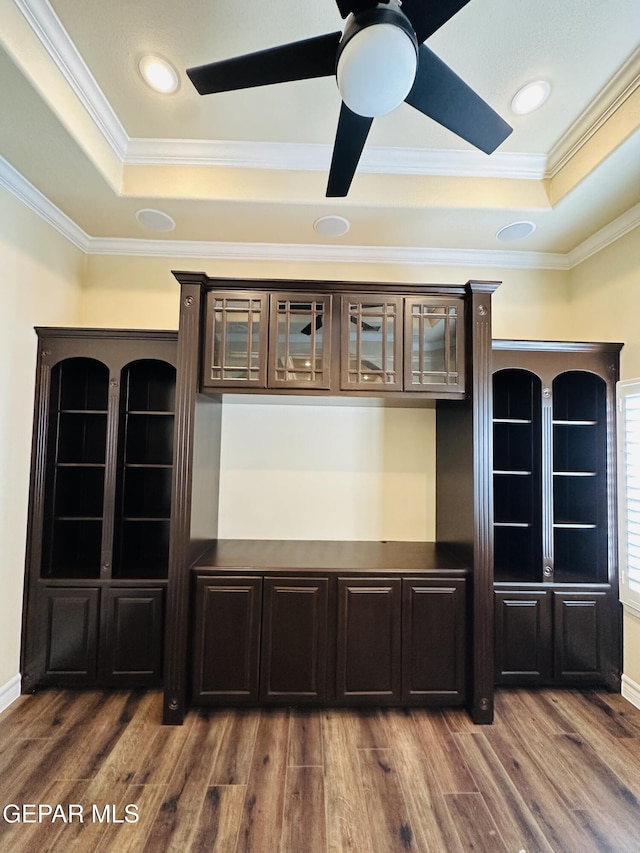 interior space with hardwood / wood-style flooring, dark brown cabinets, a raised ceiling, and crown molding