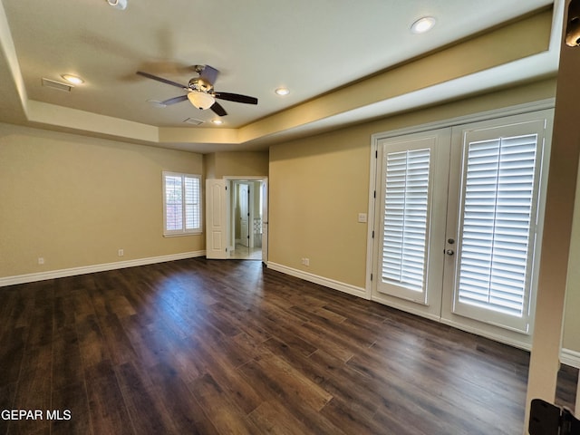 unfurnished room with ceiling fan, dark hardwood / wood-style flooring, a raised ceiling, and french doors