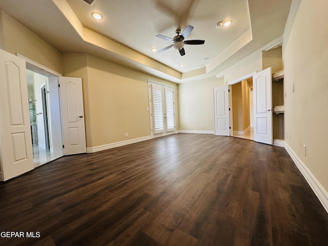 unfurnished room featuring ceiling fan, a raised ceiling, and dark wood-type flooring