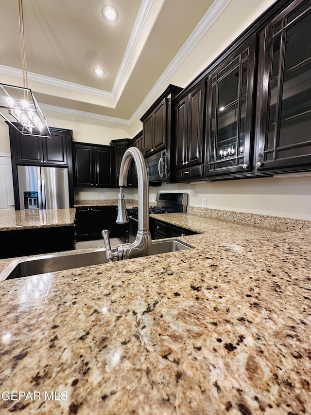 kitchen with decorative light fixtures, light stone countertops, stainless steel appliances, and ornamental molding