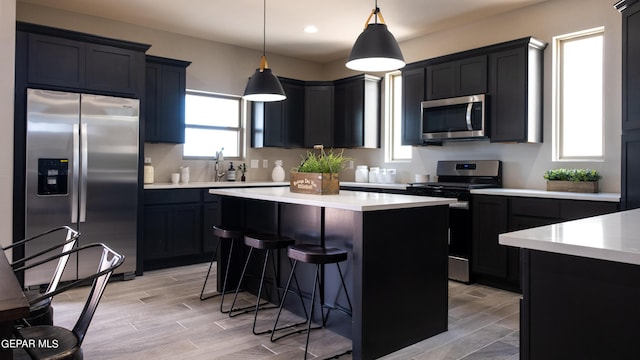 kitchen with a kitchen breakfast bar, a center island, stainless steel appliances, and decorative light fixtures