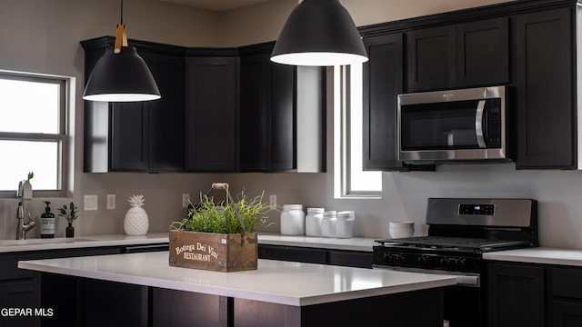 kitchen with appliances with stainless steel finishes, a kitchen island, pendant lighting, and sink