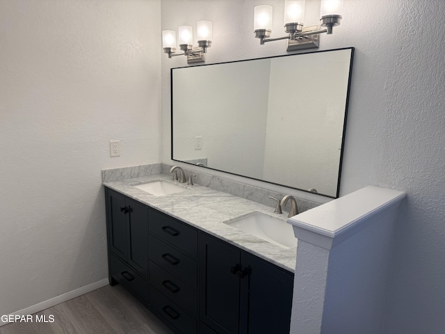 full bathroom featuring double vanity, wood finished floors, a sink, and baseboards