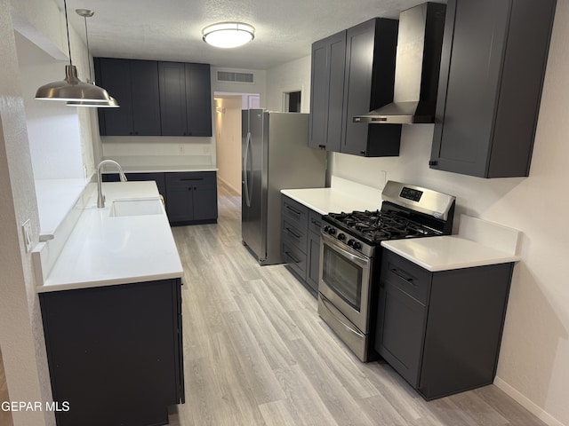 kitchen featuring a sink, visible vents, light countertops, appliances with stainless steel finishes, and wall chimney range hood