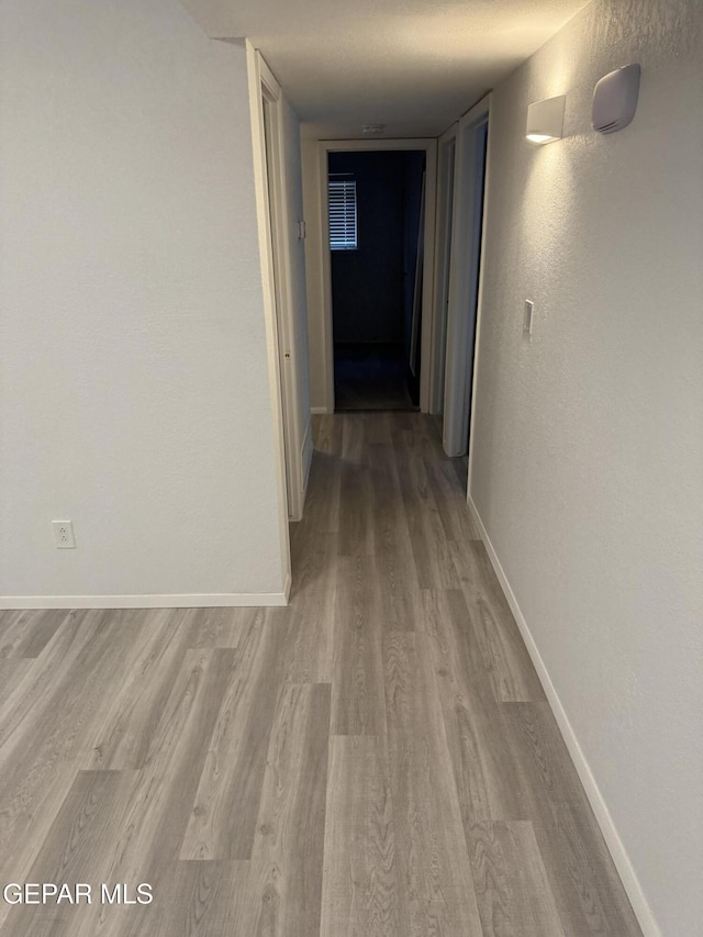 corridor with light wood finished floors and baseboards