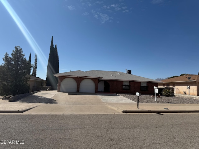 single story home with concrete driveway, brick siding, and an attached garage