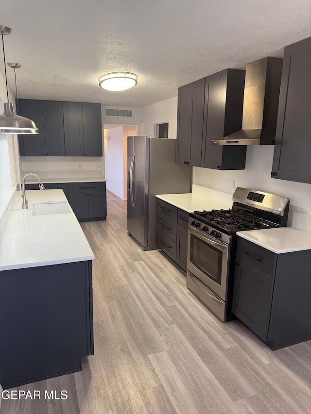 kitchen with light countertops, visible vents, appliances with stainless steel finishes, a sink, and wall chimney exhaust hood