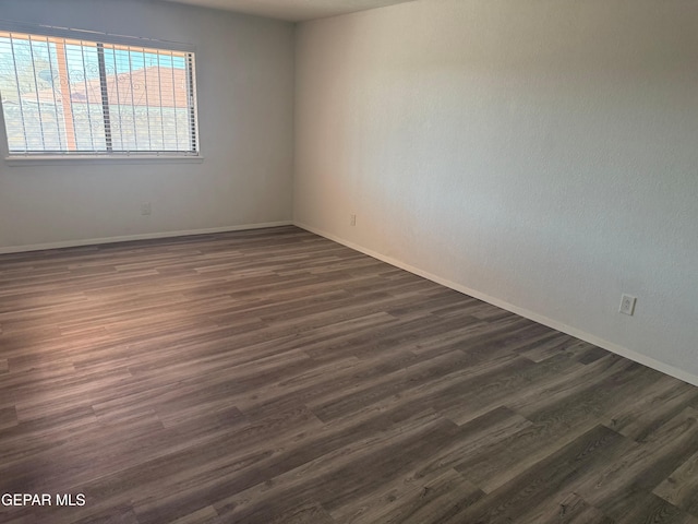 spare room with dark wood-style floors and baseboards