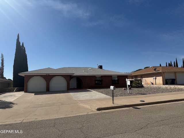 ranch-style house featuring a garage, concrete driveway, and brick siding