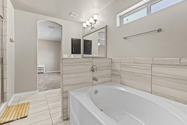 bathroom featuring tile patterned floors, vanity, a bath, and a textured ceiling