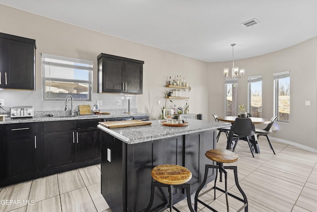 kitchen featuring tasteful backsplash, a breakfast bar, sink, an inviting chandelier, and a center island