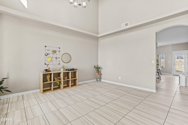 tiled spare room featuring a notable chandelier